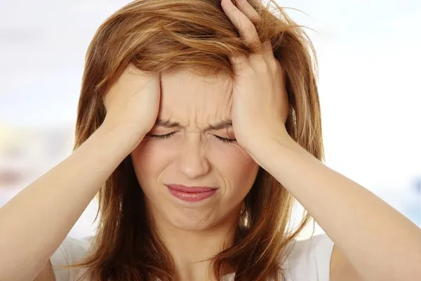 Concept of mental health. Woman sitting on couch and doing calming breathing exercises after panic attack. Female holding head in frustration. Self-control, anxiety relief concept